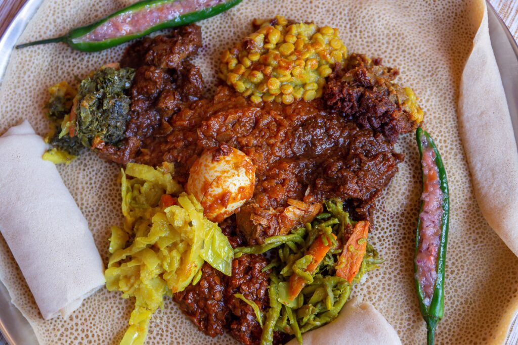 Injera served with Chicken and egg, Doro Wat, berbere, vegetables and lentils